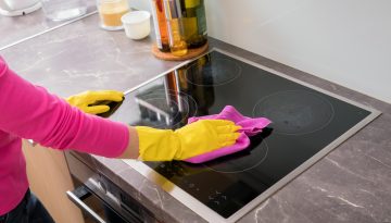 Person cleaning the stove in kitchen